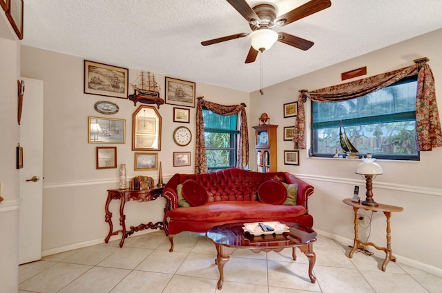 sitting room featuring ceiling fan, light tile patterned floors, and a textured ceiling