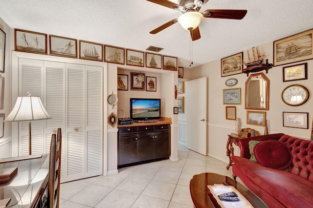 living room featuring a textured ceiling, ceiling fan, and light tile patterned flooring