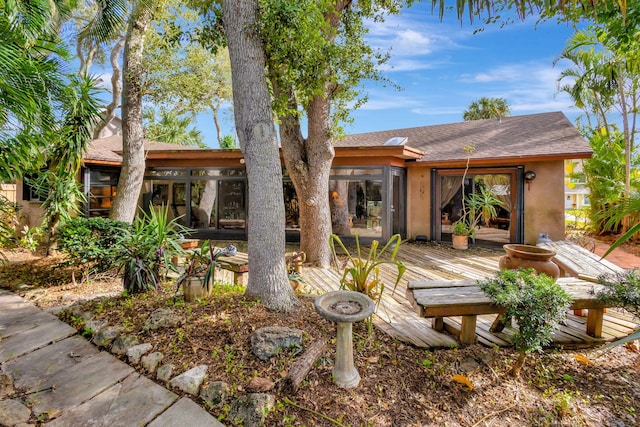 rear view of house with a wooden deck and a sunroom