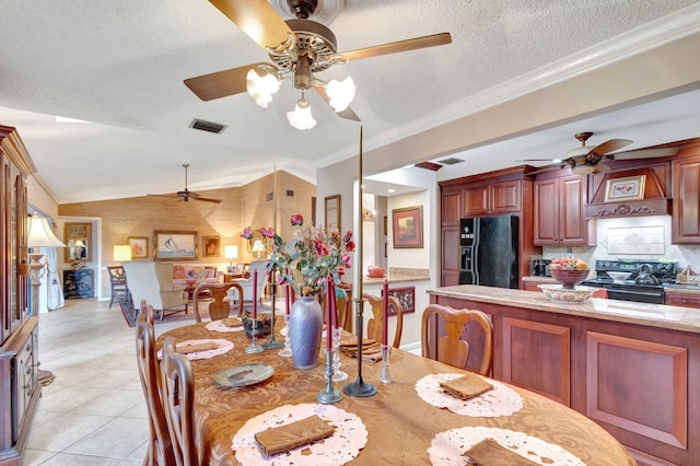 dining room with a textured ceiling, light tile patterned flooring, crown molding, and vaulted ceiling