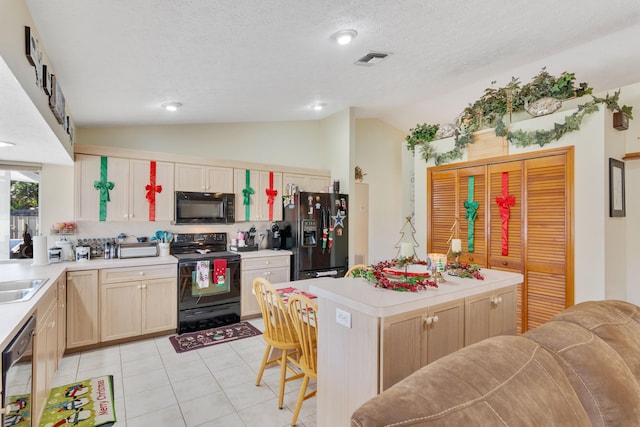 kitchen with sink, a textured ceiling, vaulted ceiling, light brown cabinetry, and black appliances