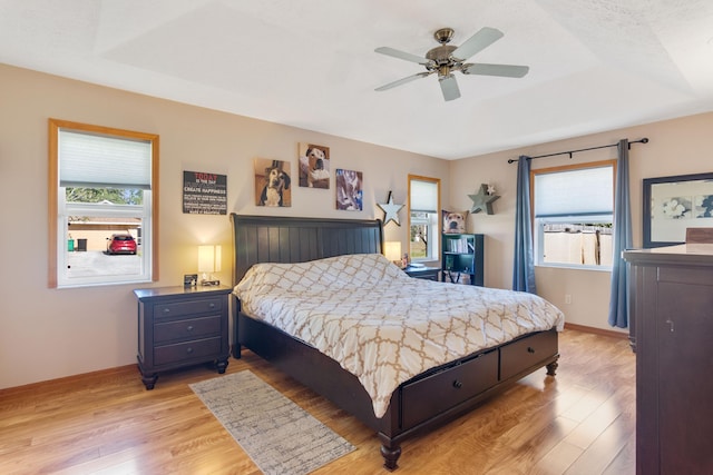 bedroom featuring a raised ceiling, ceiling fan, and light hardwood / wood-style floors