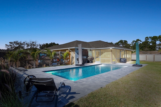 view of swimming pool featuring a lawn, a patio area, and a sunroom