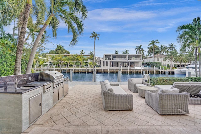 view of patio / terrace featuring sink, a grill, a water view, and exterior kitchen