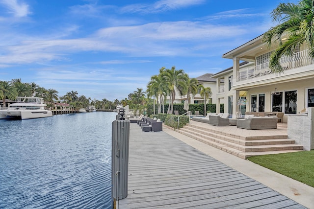 view of dock featuring an outdoor living space, a water view, and a balcony