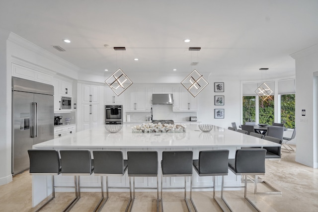 kitchen with built in appliances, hanging light fixtures, and a large island with sink