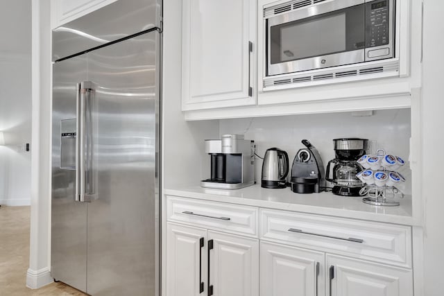 interior space with built in appliances, white cabinetry, and light tile patterned floors