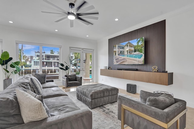 living room featuring crown molding, french doors, ceiling fan, and light wood-type flooring