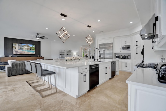 kitchen featuring pendant lighting, built in appliances, ceiling fan, and a spacious island