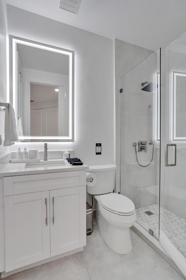 bathroom with tile patterned flooring, vanity, toilet, and a shower with shower door