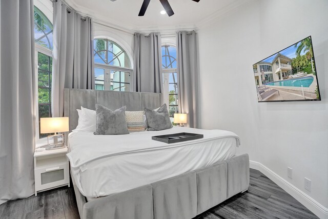 bedroom with ceiling fan, dark hardwood / wood-style floors, ornamental molding, and multiple windows