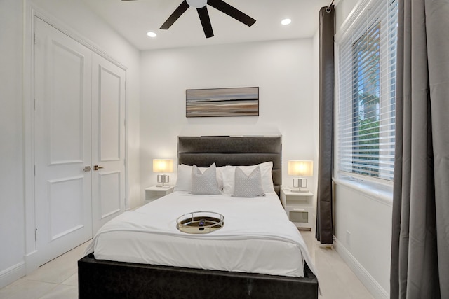 bedroom featuring ceiling fan, light tile patterned floors, and a closet