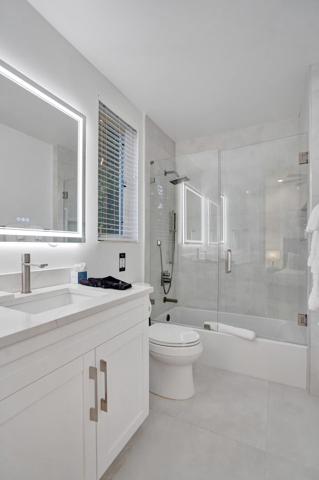 full bathroom with combined bath / shower with glass door, vanity, toilet, and tile patterned flooring