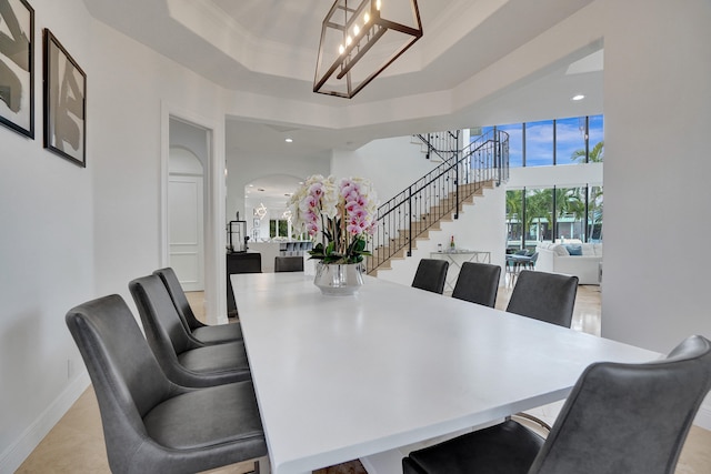 dining area with a raised ceiling, crown molding, and a chandelier