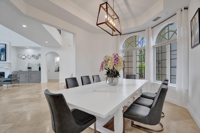 dining space with ornamental molding, a tray ceiling, and a chandelier