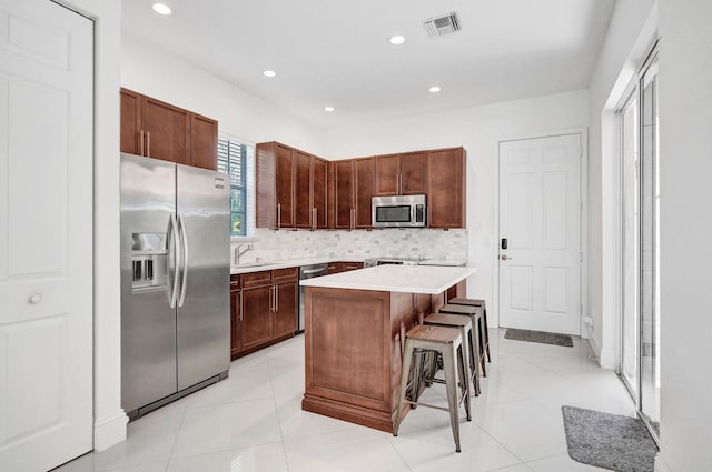 kitchen with sink, a center island, a kitchen breakfast bar, tasteful backsplash, and appliances with stainless steel finishes