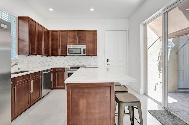 kitchen with plenty of natural light, a center island, a kitchen bar, and appliances with stainless steel finishes