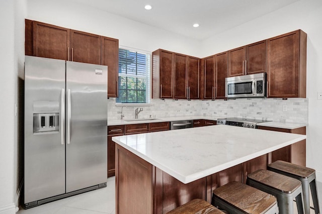 kitchen featuring a breakfast bar, sink, decorative backsplash, appliances with stainless steel finishes, and a kitchen island