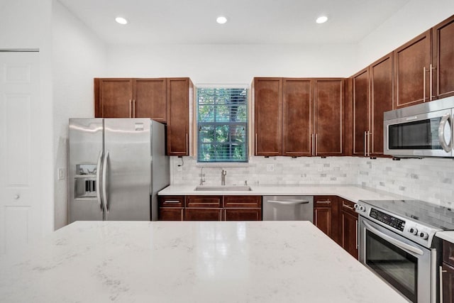 kitchen featuring decorative backsplash, stainless steel appliances, light stone countertops, and sink