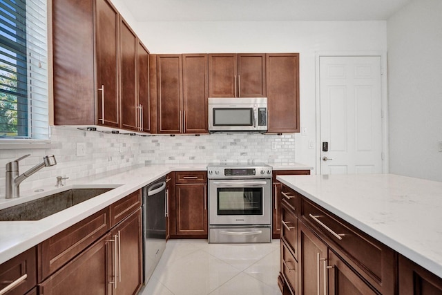 kitchen with light stone countertops, sink, decorative backsplash, light tile patterned floors, and appliances with stainless steel finishes