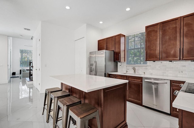 kitchen with a kitchen bar, a center island, stainless steel appliances, and a wealth of natural light