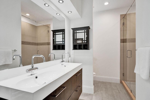 bathroom with wood-type flooring, vanity, toilet, and a shower with door