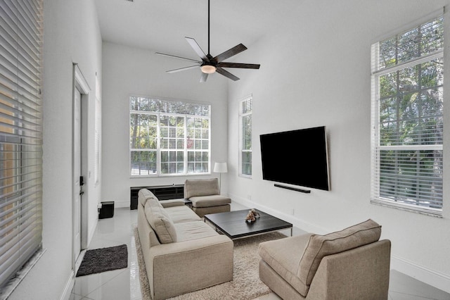 tiled living room featuring a towering ceiling, plenty of natural light, and ceiling fan