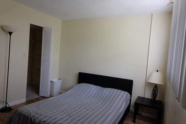 bedroom featuring a textured ceiling, dark hardwood / wood-style floors, and a closet