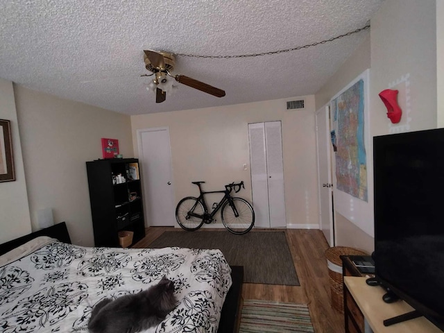 bedroom featuring dark hardwood / wood-style floors, ceiling fan, a textured ceiling, and a closet