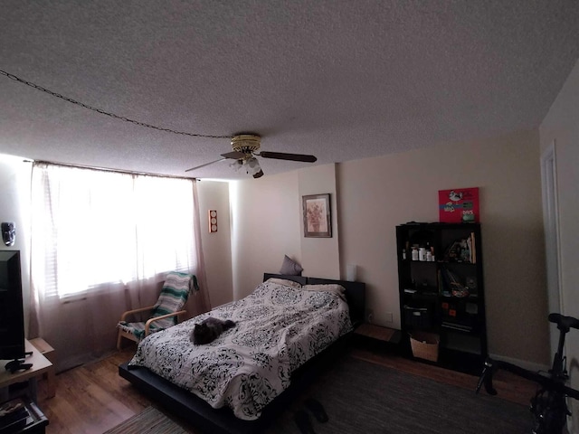 bedroom with hardwood / wood-style floors, a textured ceiling, and ceiling fan