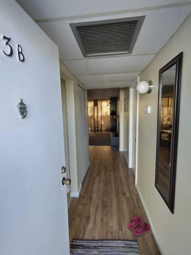 hallway with a paneled ceiling and dark hardwood / wood-style floors