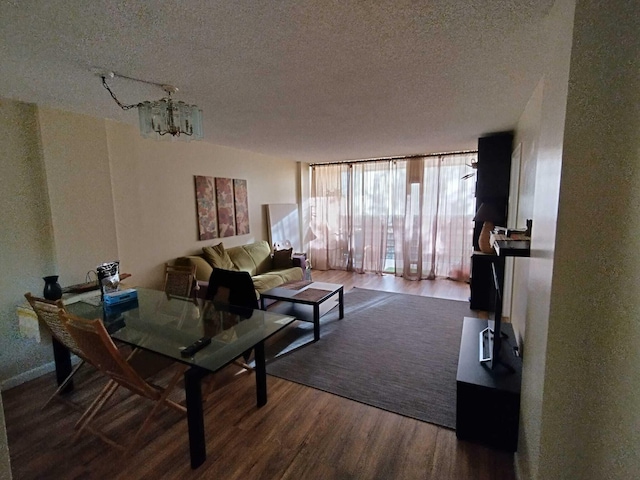 living room with hardwood / wood-style floors, a notable chandelier, a wall of windows, and a textured ceiling