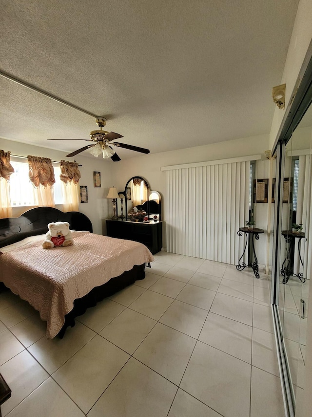 bedroom featuring a textured ceiling, light tile patterned flooring, and a ceiling fan