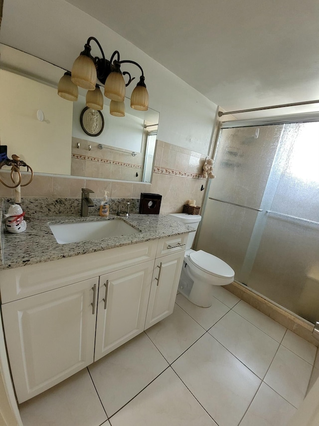 full bath with tile walls, toilet, a stall shower, vanity, and tile patterned floors