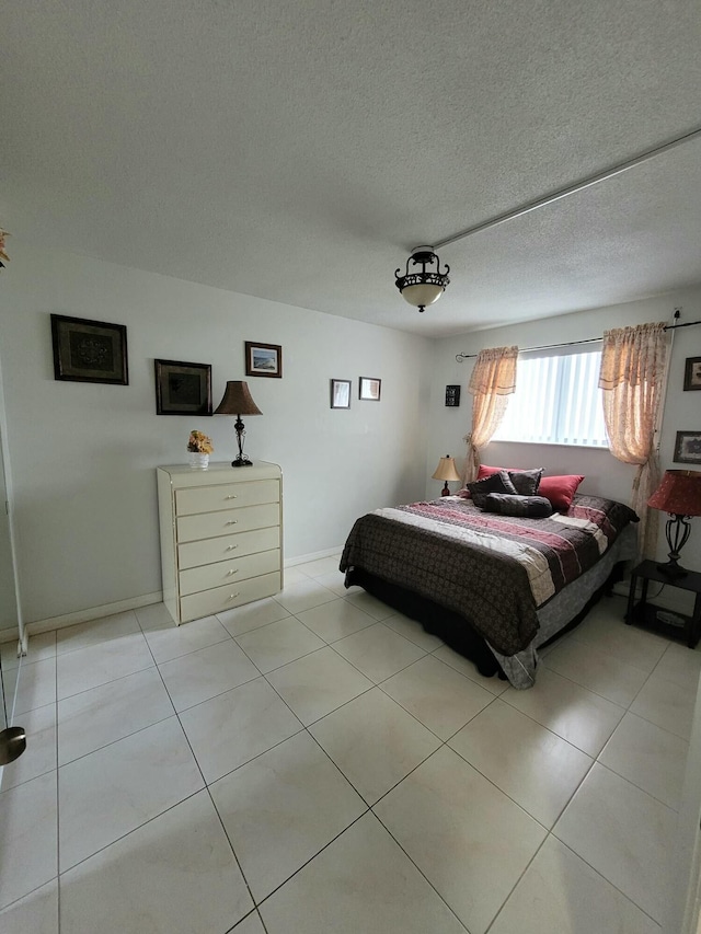 bedroom with light tile patterned flooring, a textured ceiling, and baseboards