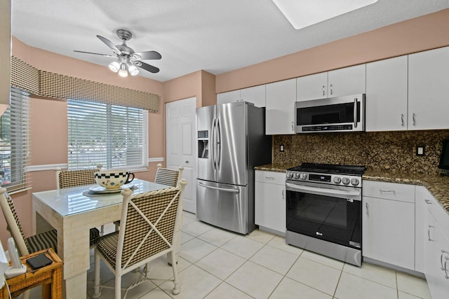 kitchen with white cabinetry, backsplash, dark stone countertops, light tile patterned flooring, and appliances with stainless steel finishes