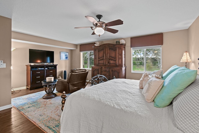 bedroom featuring multiple windows, ceiling fan, and dark hardwood / wood-style flooring