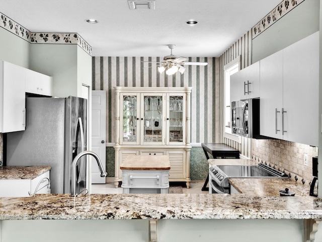 kitchen featuring kitchen peninsula, white cabinetry, ceiling fan, and stainless steel appliances