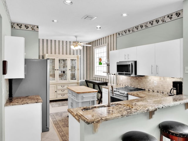 kitchen with white cabinets, a breakfast bar, kitchen peninsula, and stainless steel appliances