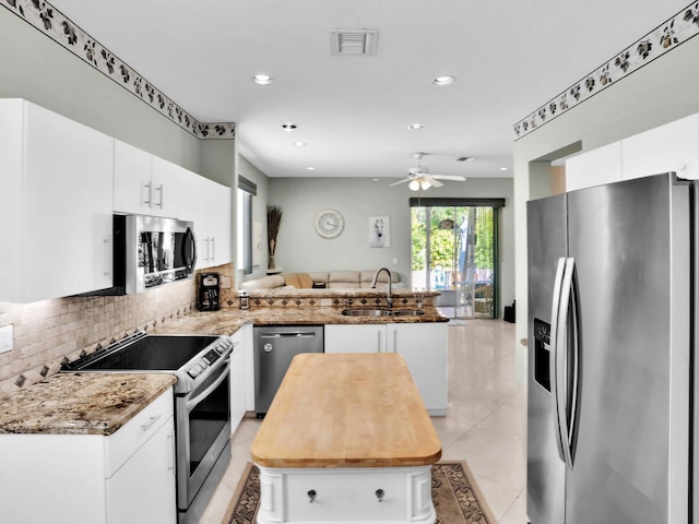 kitchen with ceiling fan, sink, kitchen peninsula, white cabinets, and appliances with stainless steel finishes