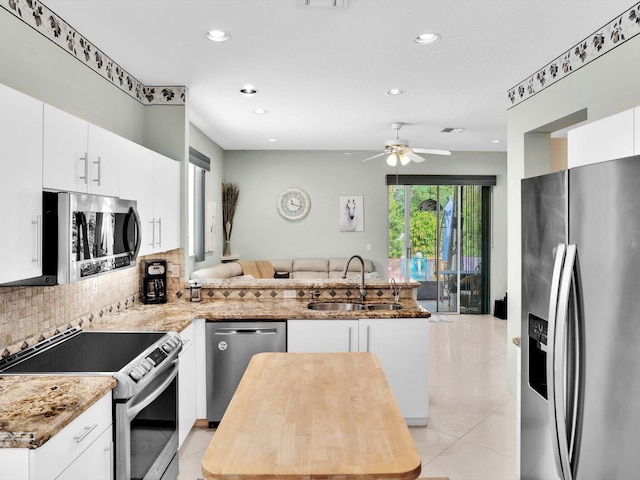 kitchen with kitchen peninsula, appliances with stainless steel finishes, white cabinets, and sink