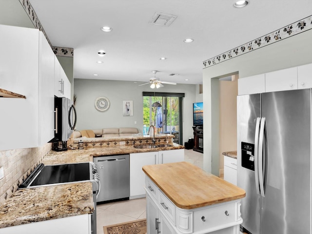 kitchen with kitchen peninsula, appliances with stainless steel finishes, sink, a center island, and white cabinetry