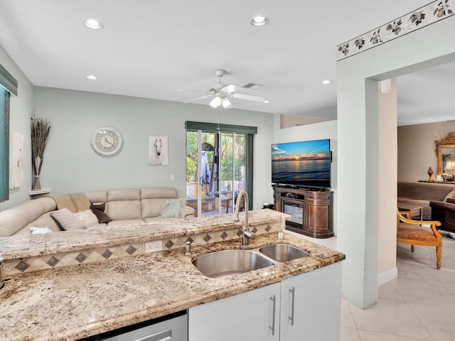 kitchen featuring ceiling fan, light stone counters, light tile patterned floors, and sink