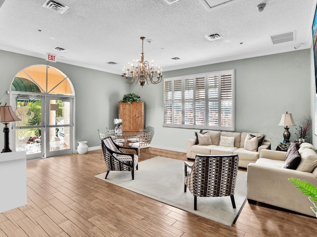 living room with a chandelier, ornamental molding, a textured ceiling, and light wood-type flooring