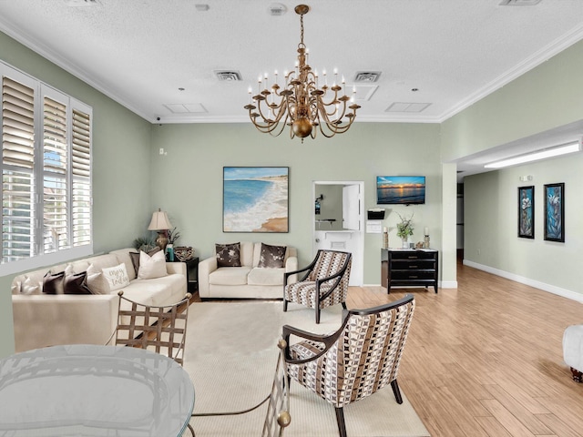 living room featuring a chandelier, a textured ceiling, light wood-type flooring, and ornamental molding