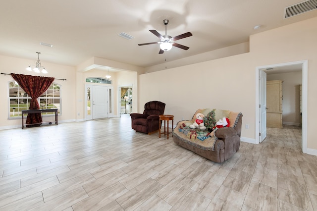 living area featuring ceiling fan with notable chandelier and light wood-type flooring