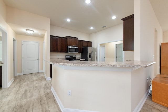 kitchen with light hardwood / wood-style floors, kitchen peninsula, and appliances with stainless steel finishes