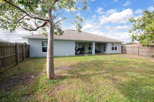 back of house with a lawn and a patio