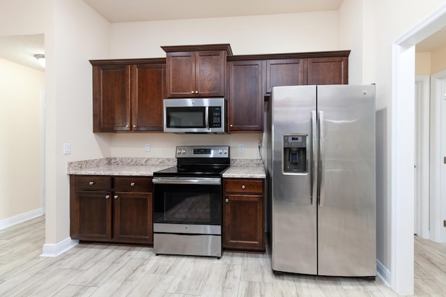 kitchen with dark brown cabinets, stainless steel appliances, and light hardwood / wood-style floors