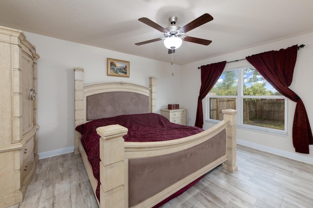 bedroom featuring ceiling fan, light hardwood / wood-style floors, and a textured ceiling